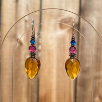 Bright topaz drops, designed by Allen Owen and made for us in Germany. Accents in fuchsia and capri are Austrian crystal. Metal trim is antiqued bronze with sterling silver ear wires. Style 463 earrings measure 1 1/2 inches long.