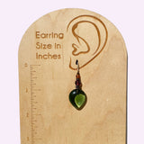 Green teardrop earring on a wooden earring size chart with measurements in inches.