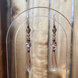 Chandelier 2-toned glass drops in light sapphire and rose, designed by Allen Owen and made for us in Germany. Accents are Austrian crystal in shades of smoke topaz and light amethyst. Trim is antiqued bronze from our own tooling with sterling silver ear wires. Metro 7 earrings measure 2 1/4 inches in length. All handwork done in the USA.