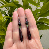 Purple glass prism earring held in a hand.
