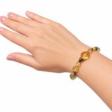 A beaded bracelet with faceted yellow and orange beads and small dark spacer beads, shown worn on a person's wrist against a plain white background.