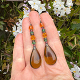 Olive colored glass earrings held in a hand. German and Czech glass with Austrian crystal. Handmade earrings.