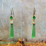 Green earrings in front of painted background.