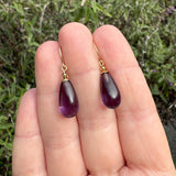 Amethyst teardrop earrings on a hand with a natural background