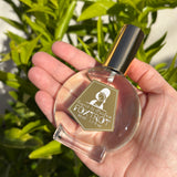 Perfume bottle labeled 'Foxy Trot' held in a hand with a green leafy background