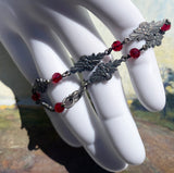 Decorative bracelet with red beads and floral designs on a mannequin hand.