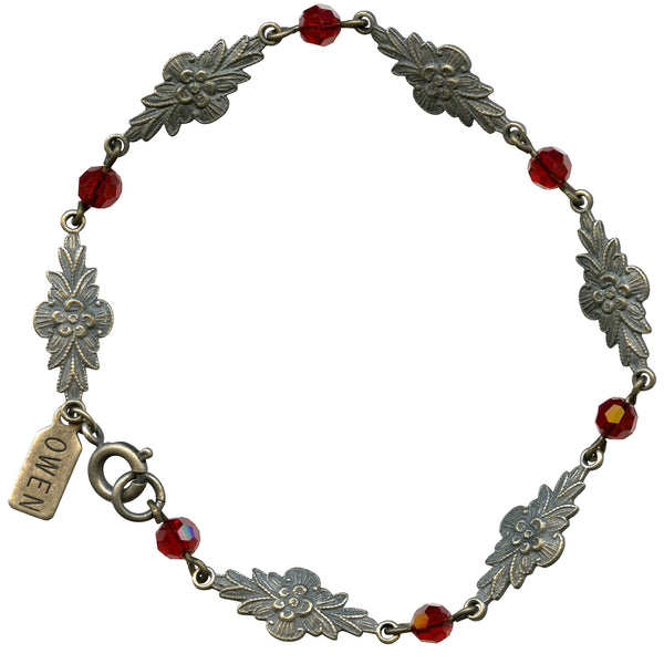 Bracelet with silver floral designs and red beads on a white background