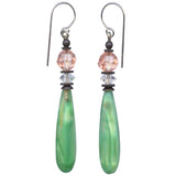 A pair of drop earrings featuring elongated green teardrop-shaped beads, clear faceted spacer beads, and pale pink faceted top beads on silver-tone French hook wires, set against a plain white background.