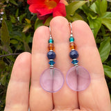 Light amethyst glass earrings held in a hand.