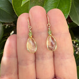 Yellow and green glass earrings held in a hand with a natural background.