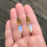 Frosted iridescent yellow glass earrings held in a hand. 