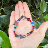 Colorful beaded bracelet on a hand with green leaves in the background