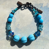 Blue beaded bracelet on a textured light gray background