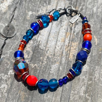 Beaded bracelet with blue, red, and orange beads on a wooden surface