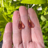 Peach glass earrings with gold trim.