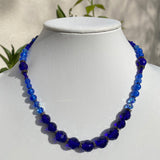 Blue beaded necklace on a mannequin with a neutral background