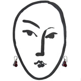 Black line drawing of a face with red earrings on a white background