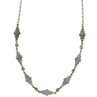 Decorative necklace with floral designs and gold accents on a white background
