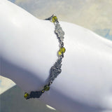 Bracelet with green beads and silver floral designs on a white surface