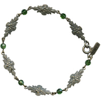 Silver bracelet with floral designs and green beads on a white background