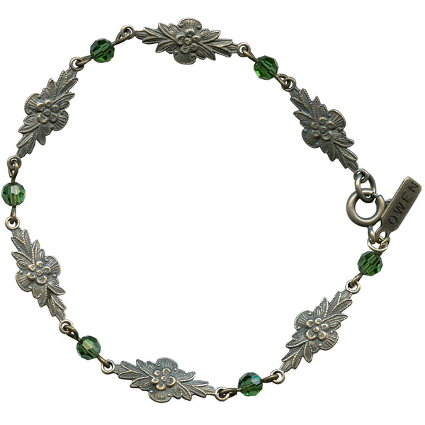 Silver bracelet with floral designs and green beads on a white background