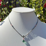 Necklace with green pendant on a mannequin against a natural background