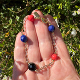 Gold bracelet held in hand with a leafy background. Glass beads are Czech glass and Japanese glass.