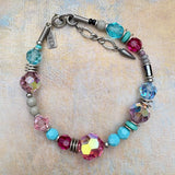 Multicolored beaded bracelet with a silver clasp on a textured beige background