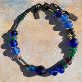 Blue glass bracelet on painted background.