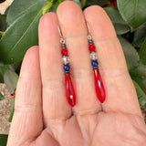 Red prism earrings held in a hand. Antique Czech glass earrings. Red, white, and blue. Handmade in the USA.